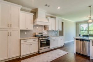 View of kitchen with island and white cabinets.